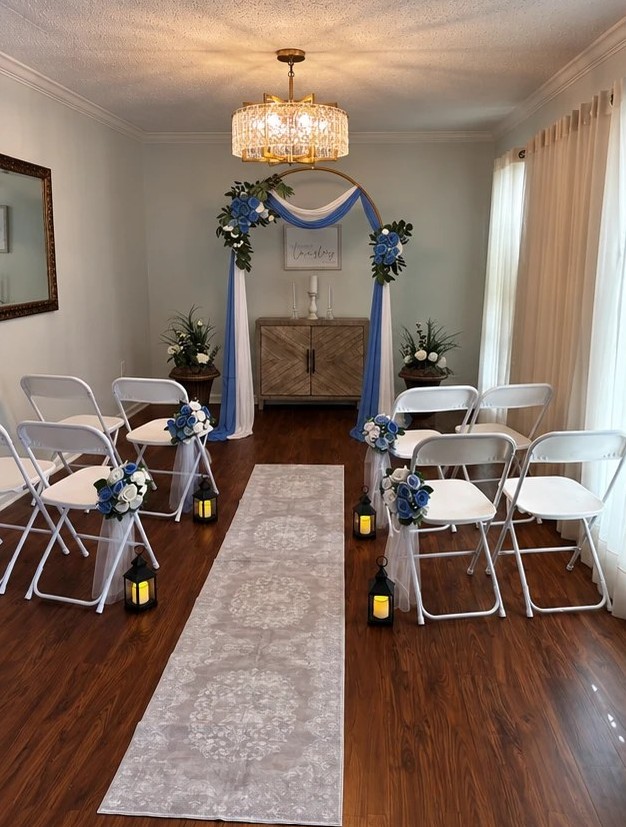 The ceremony room styled in blue and white, with a blue draped arch, blue and white flowers, and lanterns along the aisle